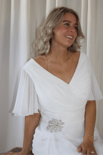 Hvid brudekjole med draperet tyl, der samles i et sølvspænde i taljen